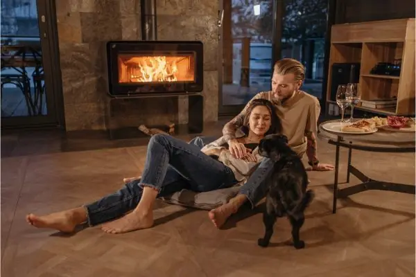 couple with a dog sitting beside the fireflace
