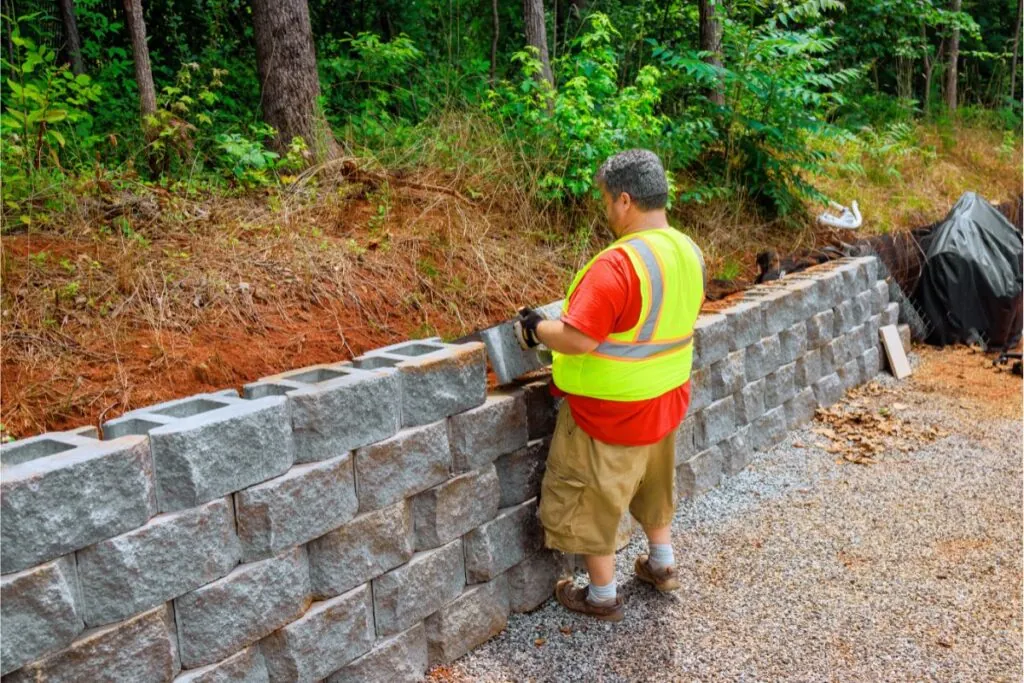 a construction worker mounted concrete blocks to retaining wall on backyard