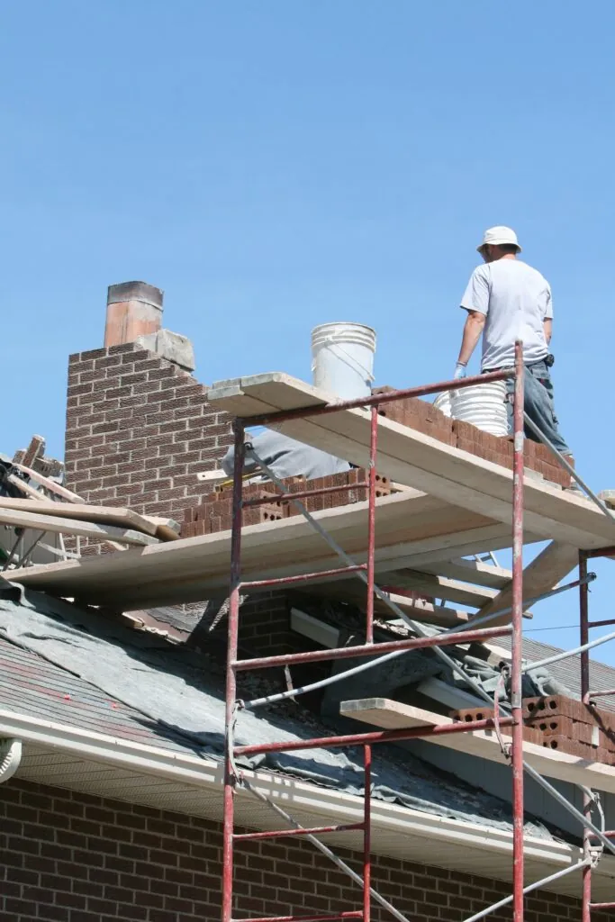 contractors repairing old chimney bricks