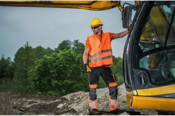 machine operator standing on hydraulic excavator assesing site