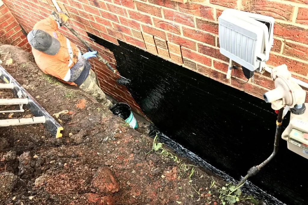 a masonry contractor waterproofing the bricks