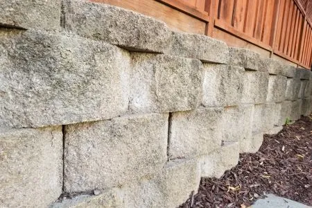 block concrete retaining wall with wooden fence